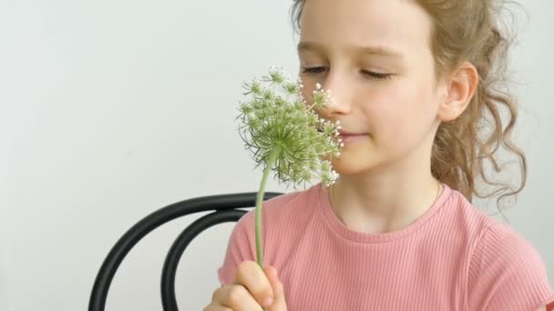 Маленькая девочка сидит дома с цветами в руках в летнее время и чихает, гиперчувствительность, астма, или аллергия концепции. — стоковое видео