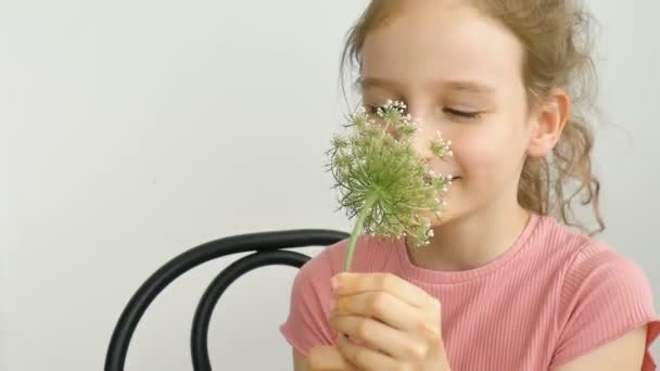 Маленькая девочка сидит дома с цветами в руках в летнее время и чихает, гиперчувствительность, астма, или аллергия концепции. — стоковое видео