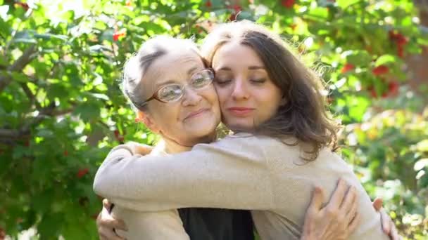 Glückliche Seniorin mit Brille umarmt ihre erwachsene Tochter, die Frauen genießen zusammen, aufrichtige Familien unterschiedlichen Alters amüsieren sich im Freien — Stockvideo