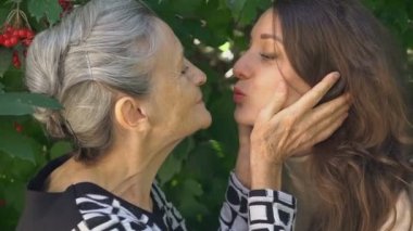 Gözlüklü mutlu kıdemli anne yetişkin kızına sarılıyor, kadınlar birlikte eğleniyor, farklı nesillerden gelen samimi aile dışarıda eğleniyor.