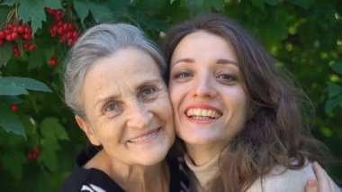 Gözlüklü mutlu kıdemli anne yetişkin kızına sarılıyor, kadınlar birlikte eğleniyor, farklı nesillerden gelen samimi aile dışarıda eğleniyor.