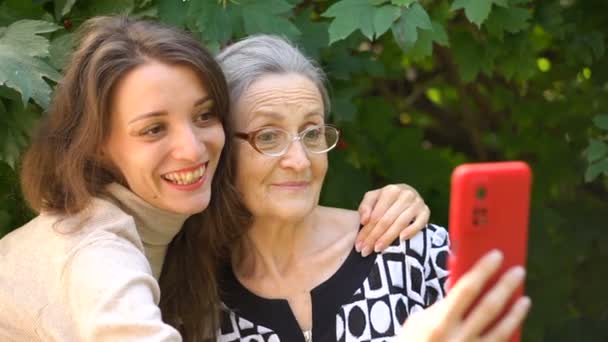 Dospělá dcera a starší maminka fotí sebe-portrét, selfie na červeném smartphonu společně, šťastný odchod do důchodu, pojetí dne matek. — Stock video