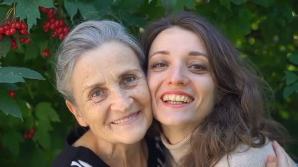 Glückliche Seniorin mit Brille umarmt ihre erwachsene Tochter, die Frauen genießen zusammen, aufrichtige Familien unterschiedlichen Alters amüsieren sich im Freien — Stockvideo