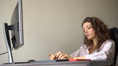 Kıvırcık saçlı ve beyaz gömlekli yorgun genç kadın ofiste bilgisayarını, rutin işini, serbest çalışmayı, tükenme sendromunu kullanarak çalışıyor.