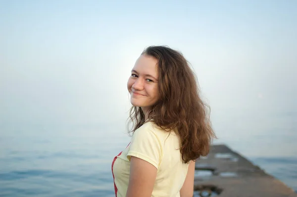 Ung flicka i gul t-shirt på havet och blå himmel bakgrund, sommar, resor, kvinnliga porträttbegrepp — Stockfoto