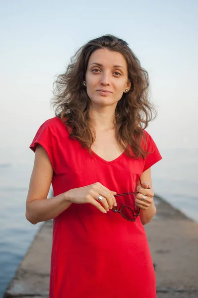 Chica joven en vestido rojo en el mar y fondo azul, verano, conceptos de viaje —  Fotos de Stock