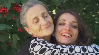 Gözlüklü mutlu kıdemli anne yetişkin kızına sarılıyor, kadınlar birlikte eğleniyor, farklı nesillerden gelen samimi aile dışarıda eğleniyor.