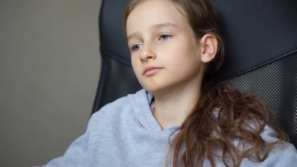 Little sad girl is sitting on black office chair, punishment, serious face — Stock Video