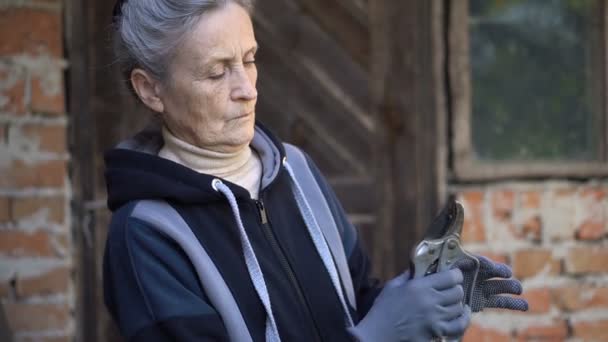 Donna anziana sta ripulendo un potatore giardino per tagliare i cespugli nel suo giardino, felice pensionamento — Video Stock
