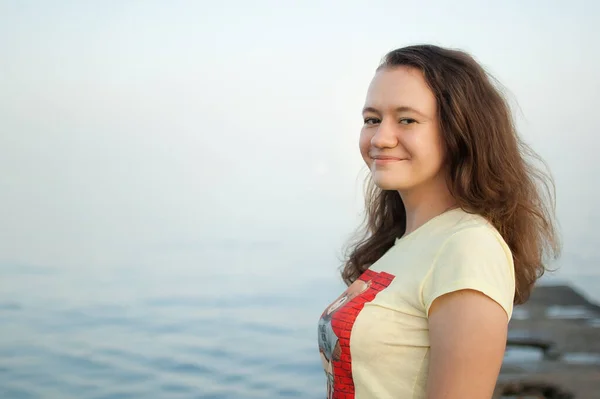Chica joven en camiseta amarilla en el fondo del mar y el cielo azul, verano, viajar, conceptos de retrato femenino — Foto de Stock
