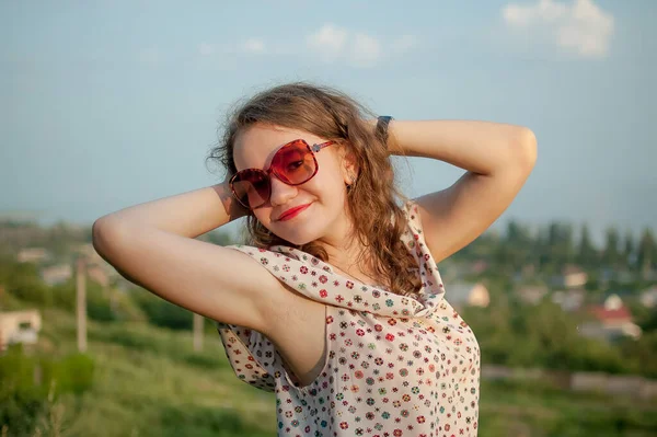 Молодая девушка в платье отлично проводит время во время летних каникул на фоне неба на природе, путешествуя по миру — стоковое фото