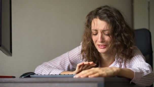 Mujer joven y cansada con el pelo rizado y camisa blanca está trabajando en la oficina usando su computadora portátil, el trabajo de rutina, freelance, síndrome de burnout — Vídeo de stock