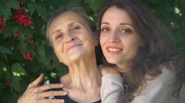 Gözlüklü mutlu kıdemli anne yetişkin kızına sarılıyor, kadınlar birlikte eğleniyor, farklı nesillerden gelen samimi aile dışarıda eğleniyor.