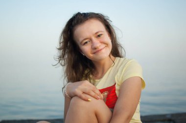 Denizde sarı tişörtlü genç kız ve mavi gökyüzü arka planı, yaz tatili, seyahat, kadın portresi konseptleri.