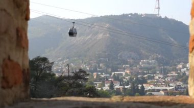 Gürcistan 'ın Tiflis şehrinin üzerinde asılı duran Cableway otomobili arka plandaki eski binalar, seyahat ve turizm kavramlarıyla