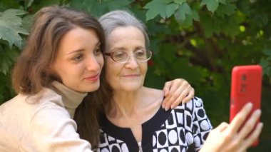 Yetişkin kız ve son sınıf annesi kendi portresini çekiyorlar, kırmızı telefondan selfie çekiyorlar, mutlu emekliler, anneler günü kavramları..
