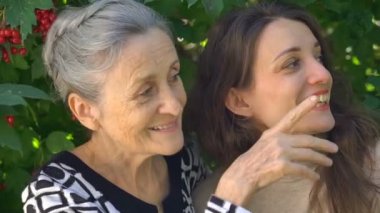 Gözlüklü mutlu kıdemli anne yetişkin kızına sarılıyor, kadınlar birlikte eğleniyor, farklı nesillerden gelen samimi aile dışarıda eğleniyor.