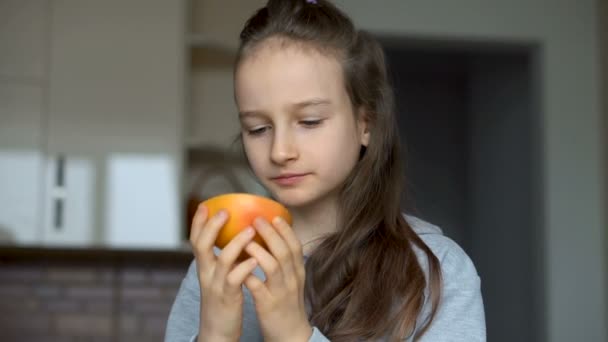 Gadis kecil dengan rambut panjang menjilati setengah jeruk. Selamat masa kanak-kanak, makanan sehat — Stok Video