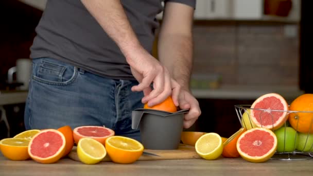 Un hombre exprime jugo de naranja con exprimidor de cítricos. Primer plano de las manos, naranjas, exprimidor, estilo de vida saludable — Vídeo de stock