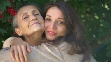 Gözlüklü mutlu kıdemli anne yetişkin kızına sarılıyor, kadınlar birlikte eğleniyor, farklı nesillerden gelen samimi aile dışarıda eğleniyor.