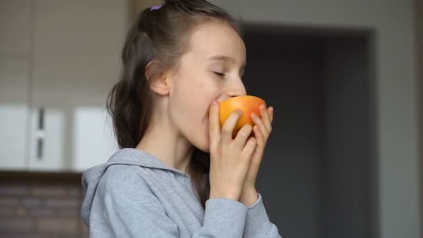 Klein meisje met lang haar likt de helft van de sinaasappel. Gelukkige kindertijd, gezond eten — Stockvideo