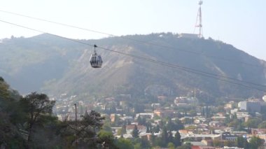 Gürcistan 'ın Tiflis şehrinin üzerinde asılı duran Cableway otomobili arka plandaki eski binalar, seyahat ve turizm kavramlarıyla