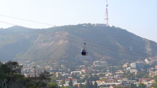 Linbanevagn hänger ovanför staden Tbilisi i Georgien med utsikt över gamla byggnader på bakgrund, resor och turism koncept — Stockvideo