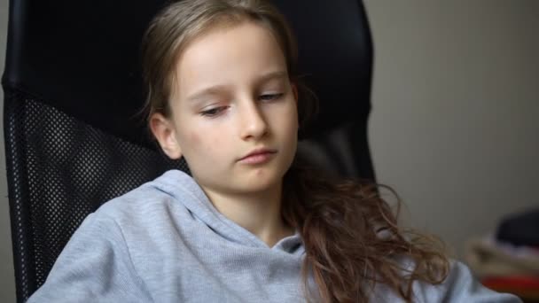 Маленька сумна дівчинка сидить на чорному офісному стільці, покарання, серйозне обличчя — стокове відео