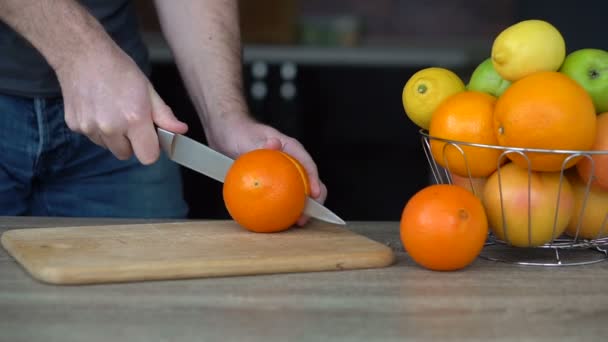Las manos masculinas están cortando naranja madura para hacer jugo de cítricos, estilo de vida saludable, jugo de frutas — Vídeos de Stock