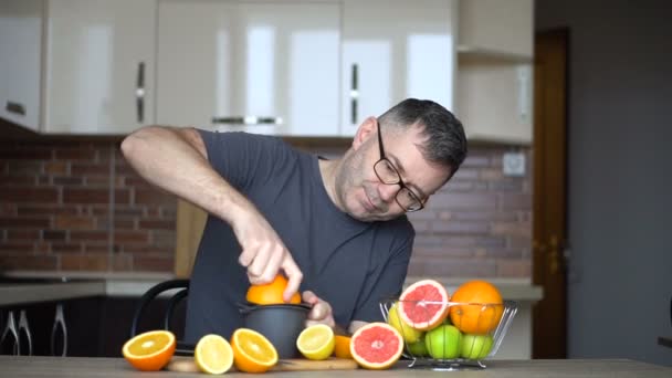 Um homem espreme sumo de laranja com sumo cítrico. Close-up de mãos, laranjas, juicer, estilo de vida saudável — Vídeo de Stock