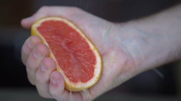 Mannelijke handen knijpen rijp grapefruit voor het maken van citrussap, gezonde levensstijl, vruchtensap — Stockvideo
