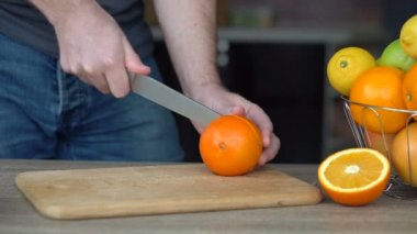 Erkek eller portakal suyu, sağlıklı yaşam tarzı ve meyve suyu yapmak için olgun portakalları kesiyor.