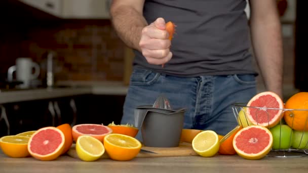 A man is squeezes orange juice with citrus juicer. Close-up of hands, oranges, juicer, healthy lifestyle — Stock Video
