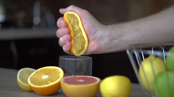 Um homem espreme sumo de laranja com sumo cítrico. Close-up de mãos, laranjas, juicer, estilo de vida saudável — Vídeo de Stock