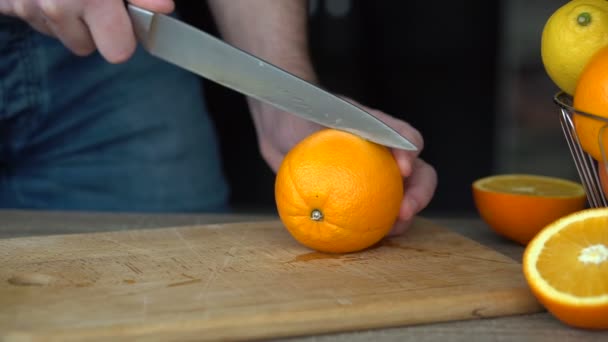 Mannelijke handen snijden rijp oranje voor het maken van citrussap, gezonde levensstijl, vruchtensap — Stockvideo