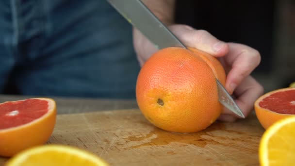 Mannelijke handen snijden rijp grapefruit voor het maken van citrussap, gezonde levensstijl, vruchtensap — Stockvideo