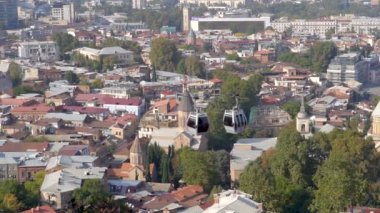 Gürcistan 'ın Tiflis şehrinin üzerinde asılı duran Cableway otomobili arka plandaki eski binalar, seyahat ve turizm kavramlarıyla