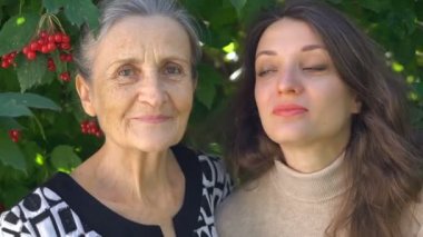 Gözlüklü mutlu kıdemli anne yetişkin kızına sarılıyor, kadınlar birlikte eğleniyor, farklı nesillerden gelen samimi aile dışarıda eğleniyor.