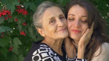 Gözlüklü mutlu kıdemli anne yetişkin kızına sarılıyor, kadınlar birlikte eğleniyor, farklı nesillerden gelen samimi aile dışarıda eğleniyor.