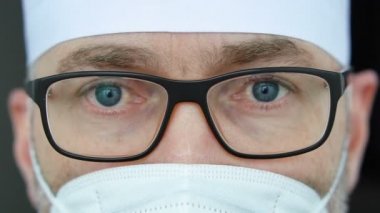 Koronavirüs salgını nedeniyle çok sayıda hasta aldıktan sonra maskeli, gözlüklü ve koruyucu süitli ciddi bir yetişkin erkek doktor yorgun düştü..