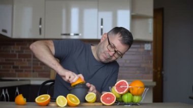 Adamın biri portakal suyunu narenciye ile sıkıyor. Eller, portakallar, meyve sıkacağı, sağlıklı yaşam tarzı.