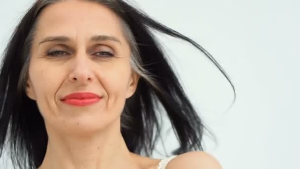 Retrato feminino de mulher de meia-idade começando a ficar grisalho no estúdio com ombros nus no fundo branco, rosto beleza cuidados da pele, cosméticos de meia-idade, conceito de cosmetologia — Vídeo de Stock