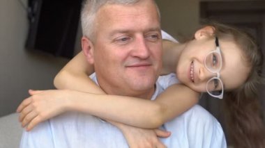 Yetişkin baba ve küçük sarışın kızın aile portresi. Babalar gününü kutlarken evde sarılıyorlar.