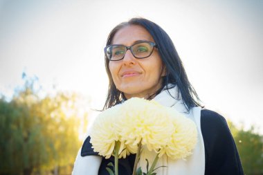 Profil yan görüntüsü: Çekici, hayalperest, gri saçlı, orta yaşlı kadın güneşli bir günde dışarıda dinleniyor.