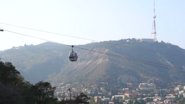 2021.10.15 - Georgia, Tbilisi - Cableway car hanging above the city with the view of old buildings on background, travelling and tourism concepts — Stock Video