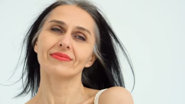 Orta yaşlı bir kadının portresi beyaz arka planda çıplak omuzlarla stüdyoda saçlarını ağartmaya başlıyor, yüz bakımı güzelliği, orta yaşlı kozmetik ürünleri, kozmetik konsepti — Stok video