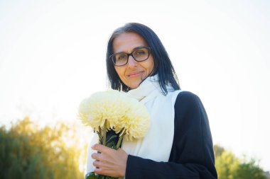 Profil yan görüntüsü: Çekici, hayalperest, gri saçlı, orta yaşlı kadın güneşli bir günde dışarıda dinleniyor.