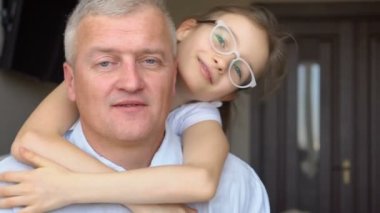 Yetişkin baba ve küçük sarışın kızın aile portresi. Babalar gününü kutlarken evde sarılıyorlar.
