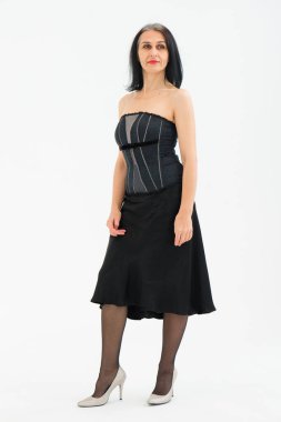 Orta yaşlı bir kadının saçları ağarmaya başlıyor. Stüdyoda siyah kıyafetler ve beyaz arka planda çoraplarla poz veriyor. Orta yaşlı seksi bayan, kozmetoloji konsepti.