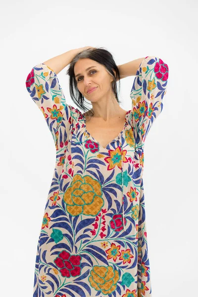 Orta yaşlı bir kadının beyaz arka planda çiçekli gri saçlı, orta yaşlı seksi bir kadın ve kozmetik konsepti olan bir elbise giymesi.